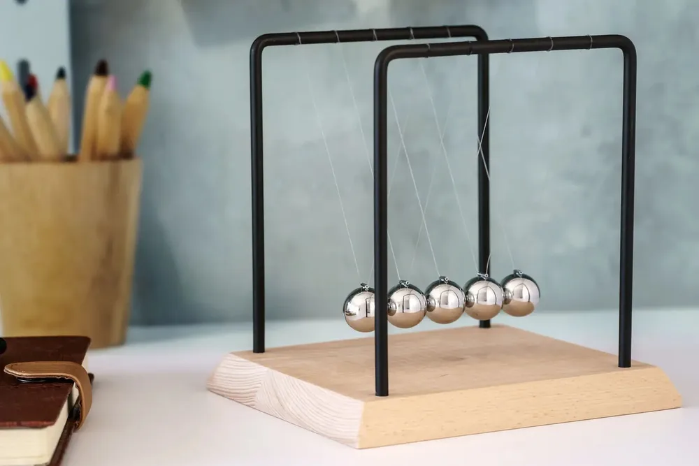 Newton's cradle with swinging metal balls on a wooden base